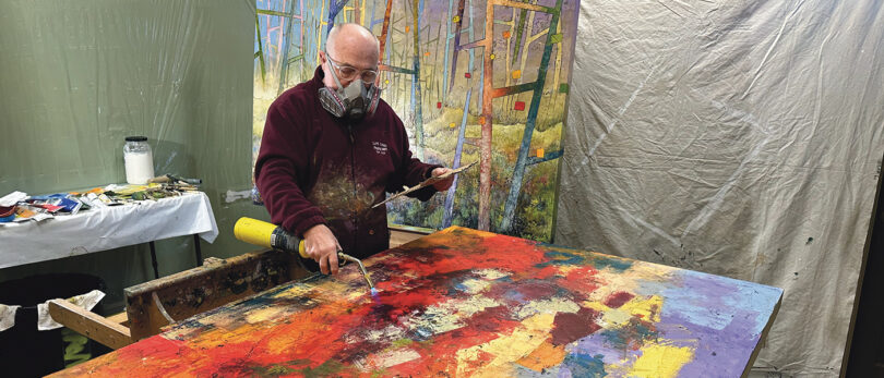 Man melting gold on painted canvas