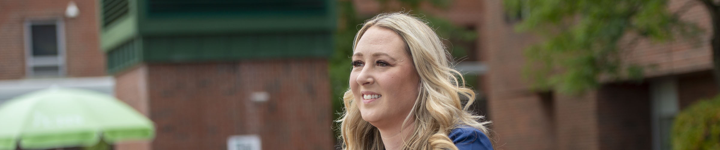Female nurse in front of a building smiling and staring far off.