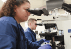Two lab technicians looking at samples through a machine.