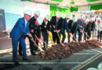Men and women in construction hats and suits breaking ground at the new UHS Upper Front Street facility.