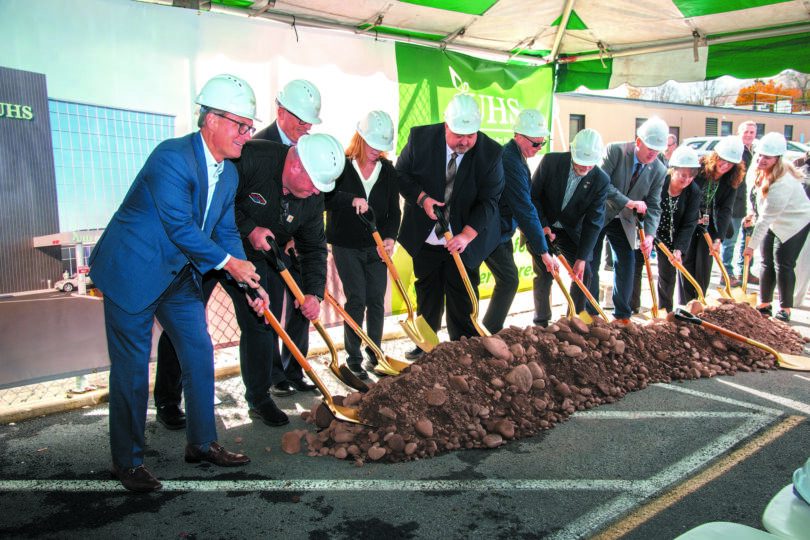 Men and women in construction hats and suits breaking ground at the new UHS Upper Front Street facility.