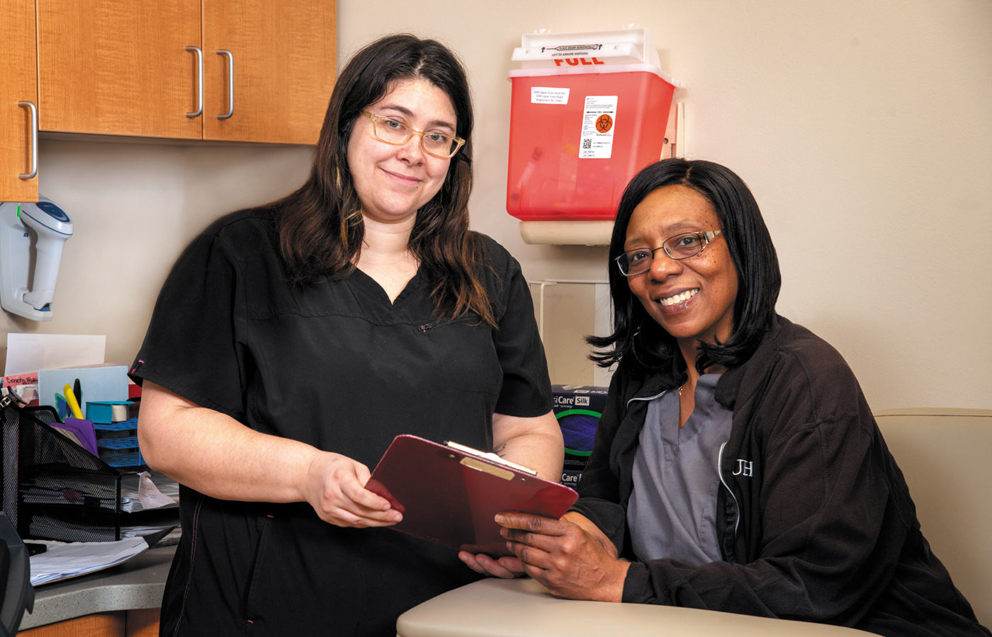 Two hospital employees standing in an exam room smiling.