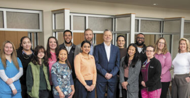 Multiple hospital employees pose for a group photo at the new UHS Upper Front Street facility.